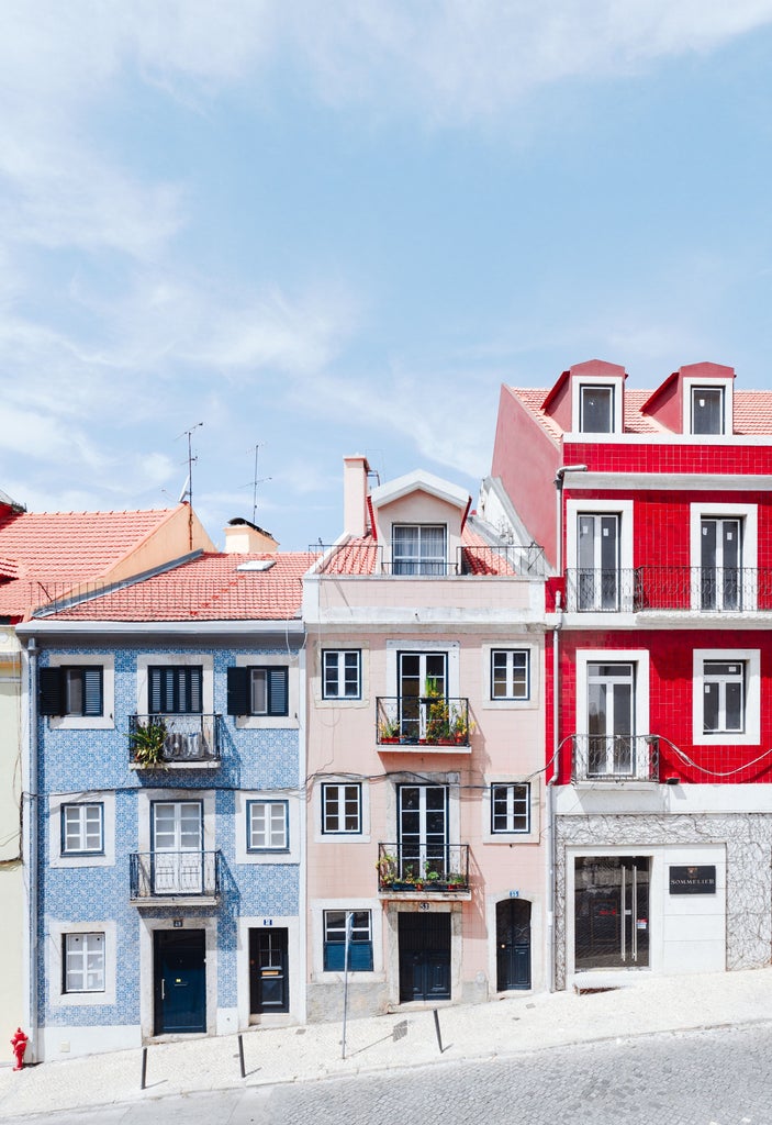 Panoramic view of Lisbon's hillside cityscape with terracotta rooftops, historic trams, and the iconic Tagus River glinting in sunlight