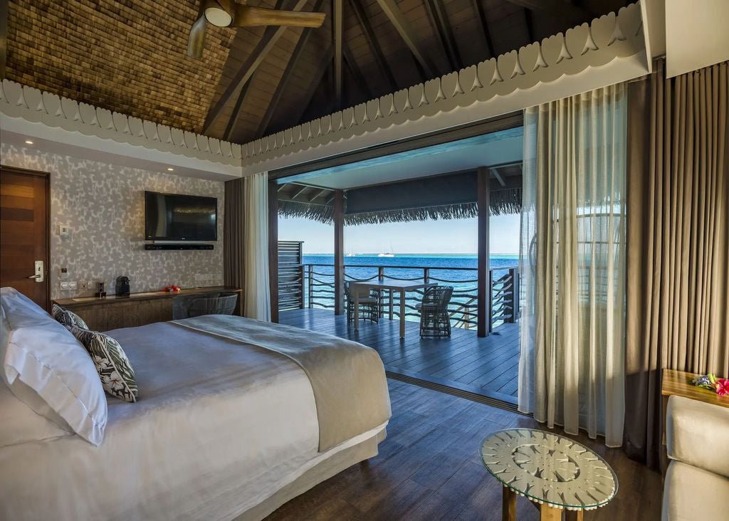 Luxurious overwater bungalow suite with private deck, turquoise lagoon views, and thatched roof, nestled in tropical Tahitian waters