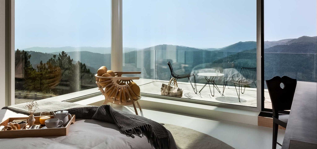 Luxurious hotel room with panoramic mountain views, elegant modern furnishings, and warm wood accents in Portugal's scenic hotel Casa de São Lourenço