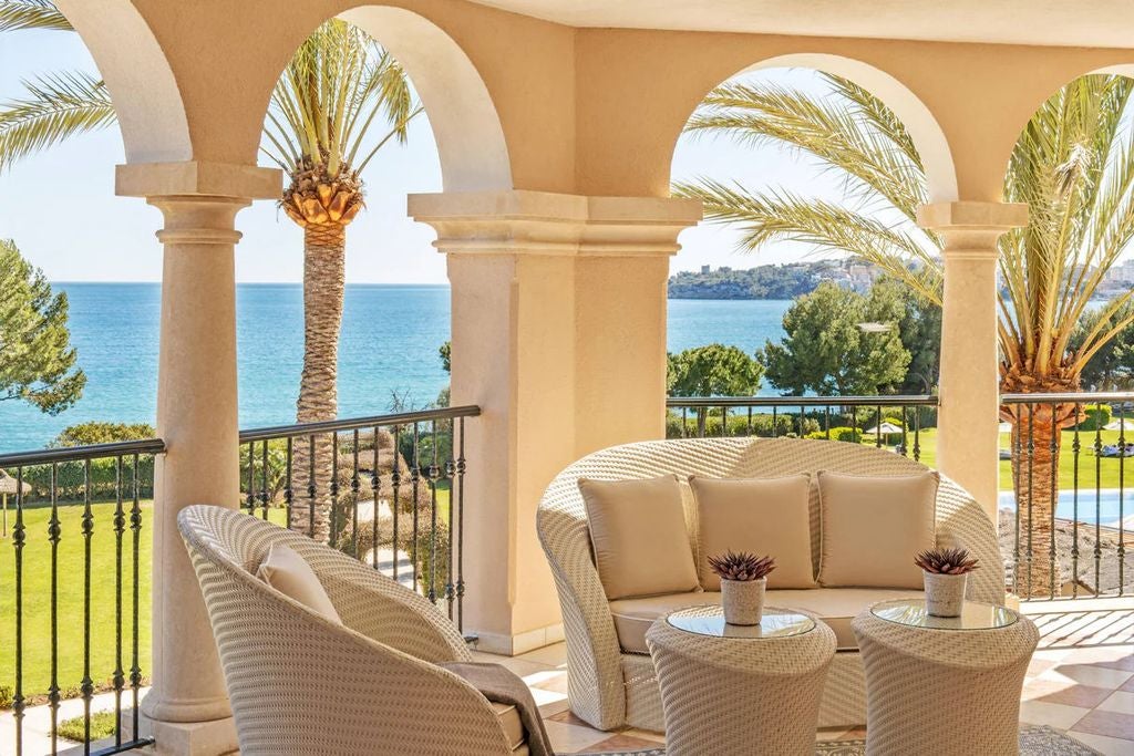 Luxury Mediterranean resort with cascading infinity pools, manicured gardens and elegant stone buildings overlooking Mallorca's coastline