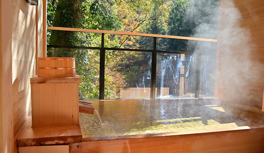 Traditional Japanese ryokan with minimalist wooden architecture, soft lighting, and elegant shoji screens overlooking a serene garden with meticulously pruned trees and stone walkways.