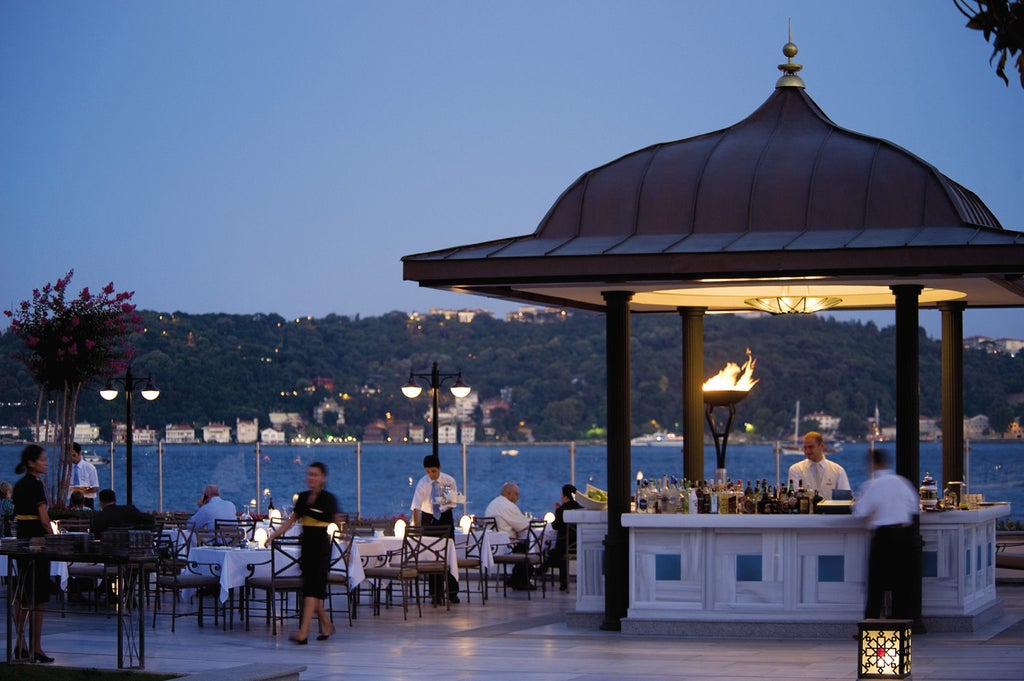 Luxurious historical palace hotel with white facade and grand arched windows overlooking the Bosphorus strait in Istanbul at sunset