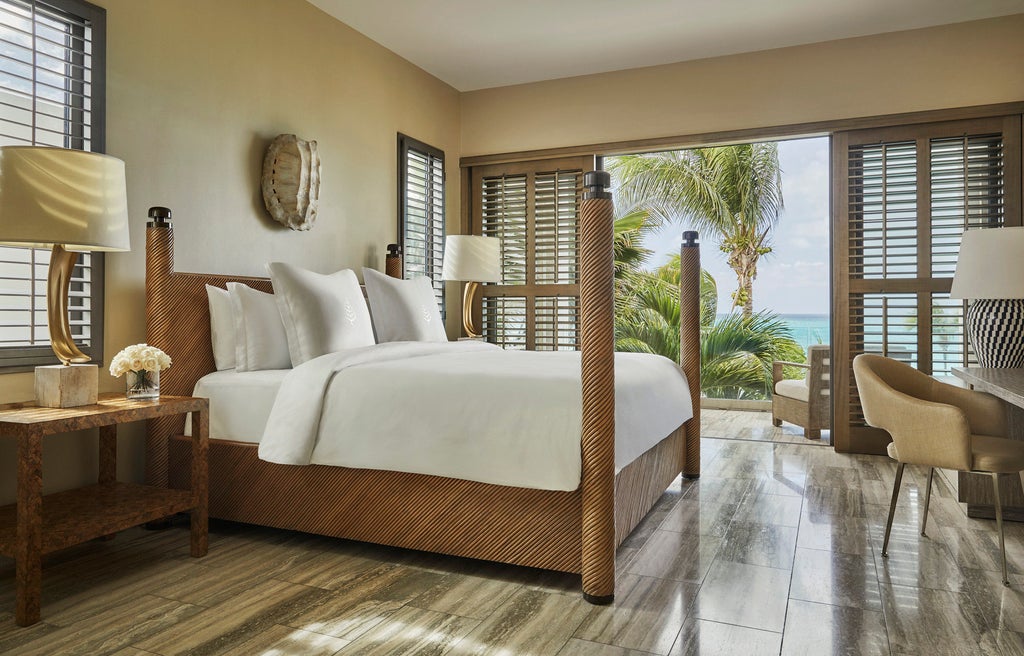 Luxurious beachfront infinity pool overlooking turquoise Caribbean waters at sunset, with modern lounge chairs and palm trees framing the view