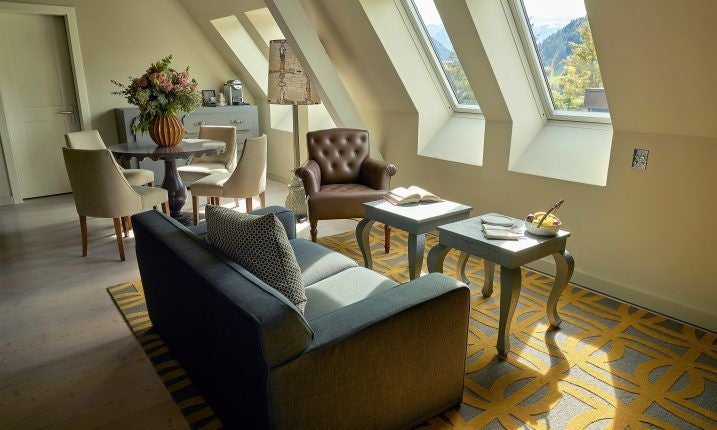 Luxurious Swiss alpine suite with panoramic mountain views, elegant marble bathroom, plush king bed, and expansive windows showcasing scenic landscape