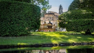 Luxurious three-story Georgian-style manor hotel with manicured gardens, elegant stone facade, and grand white exterior in scenic United Kingdom countryside