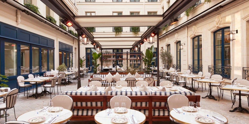 Elegant French boutique hotel facade with ornate balconies, classic Parisian architecture, and sophisticated gold-accented entryway