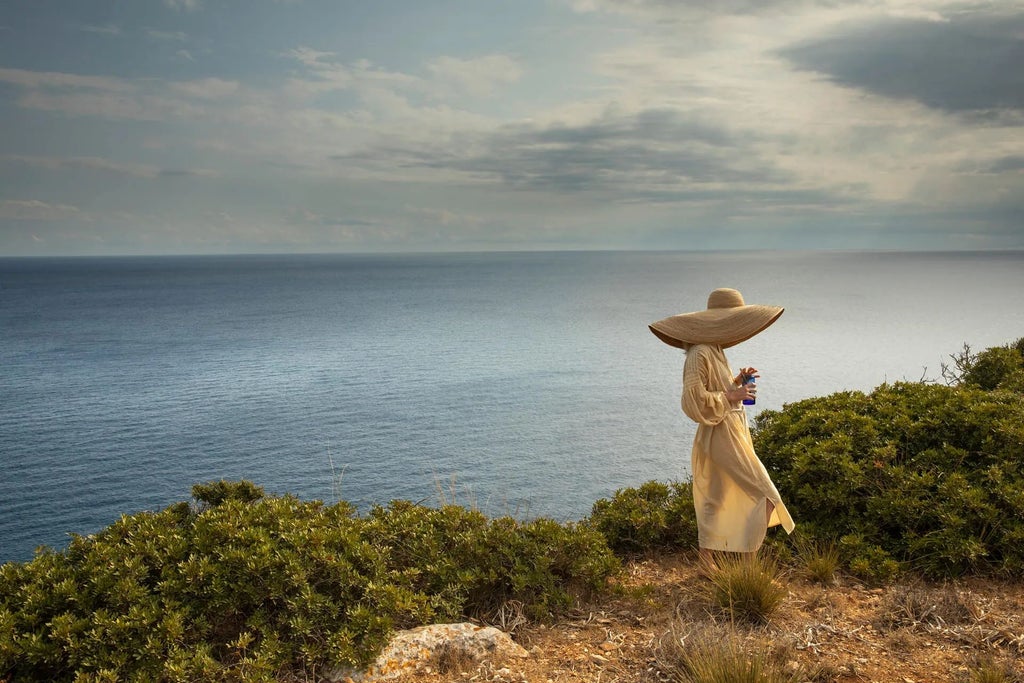 Whitewashed Mediterranean villa with elegant terrace overlooking azure coastline, rustic stone walls and lush greenery of Experimental Hotel in coastal Spain