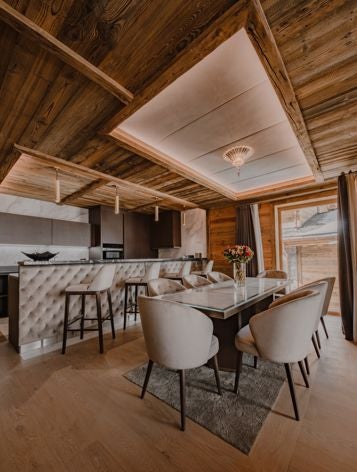 Luxurious alpine suite with modern design, featuring plush white bedding, floor-to-ceiling windows overlooking snow-capped mountains in Courchevel, France