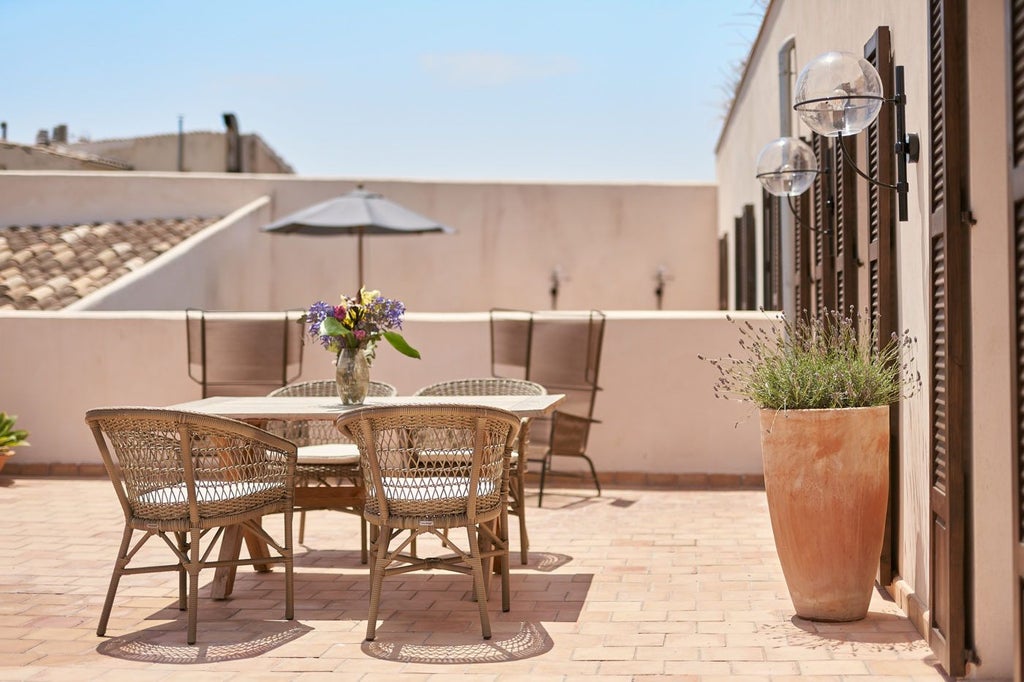 Elegant sky suite with panoramic windows, plush white bedding, and rich wooden floors overlooking lush Mediterranean garden at luxury Spanish boutique hotel