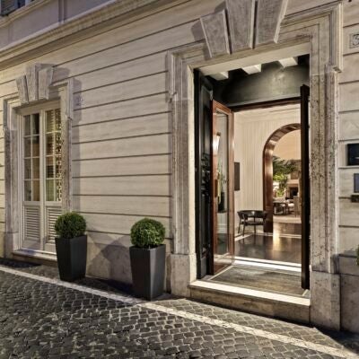 Luxurious boutique hotel facade in Rome with elegant white marble entrance, classic Italian architectural details, and sophisticated designer exterior lighting