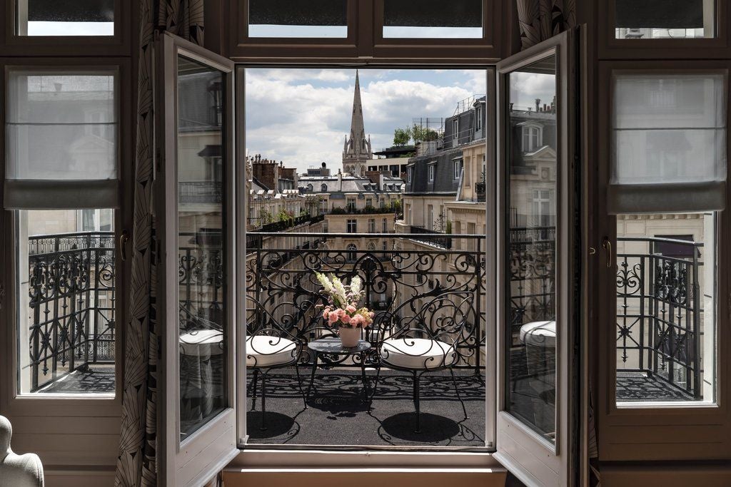 Elegant Parisian hotel facade with ornate balconies, classic French architecture, and cream-colored stone illuminated by warm lighting