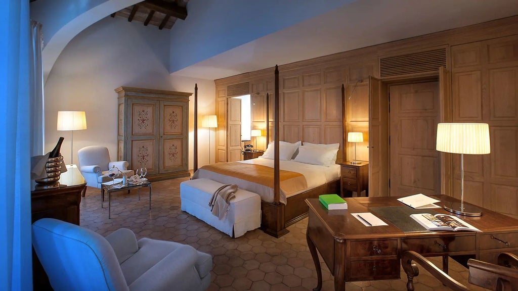 Elegant junior suite with rustic stone walls, plush king bed, and large arched windows overlooking Umbrian countryside in a historic Italian palazzo