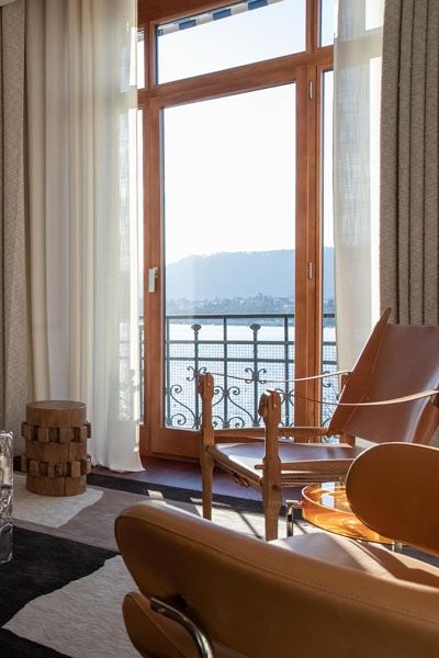 Elegant Eden Suite at La Réserve, featuring lake views, plush furnishings, soft neutral tones, and expansive windows overlooking Zurich's scenic waterfront landscape