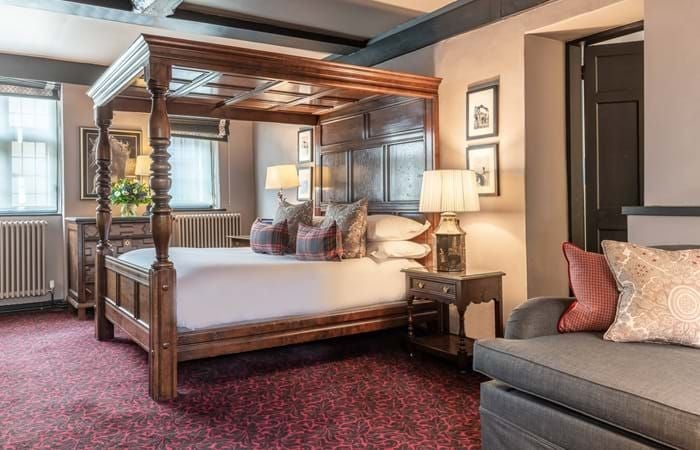 Elegant superior room with classic British decor, plush king bed, antique wooden furnishings, and large windows overlooking historic hotel courtyard at The Lygon Arms