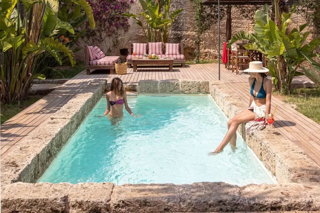 Historic Italian masseria with whitewashed stone walls, ornate archways and blooming bougainvillea surrounding a luxury pool terrace