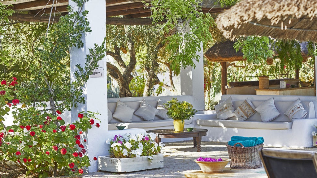 Historic Spanish hacienda with whitewashed walls, terracotta roof tiles, and elegant courtyard garden featuring manicured hedges and palm trees