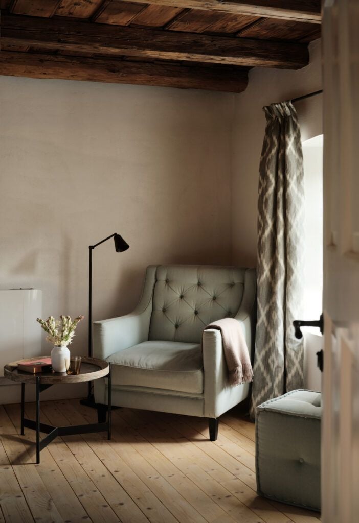 Elegant rustic bedroom in Transylvanian historic Depner House, featuring wooden floors, traditional textiles, and warm ambient lighting at Bethlen Estates