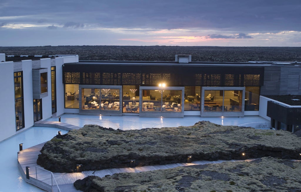 Luxurious scenset hotel nestled in rugged Icelandic landscape, featuring sleek modern architecture with floor-to-ceiling windows overlooking dramatic volcanic terrain