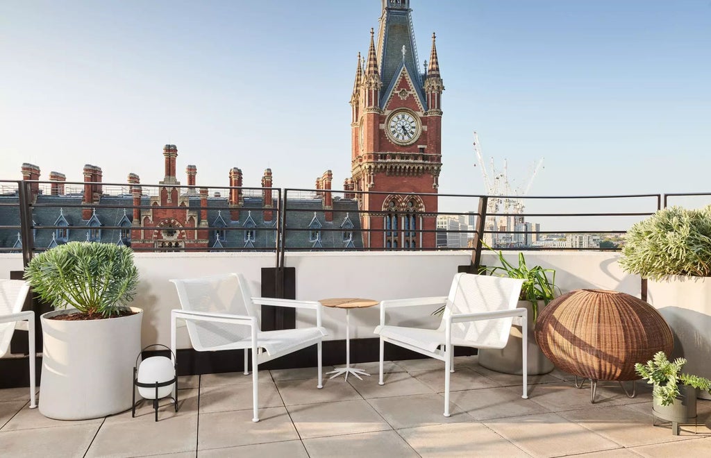 Sleek rooftop terrace of urban luxury hotel overlooking London skyline, featuring modern design with minimalist furniture and dramatic sunset backdrop