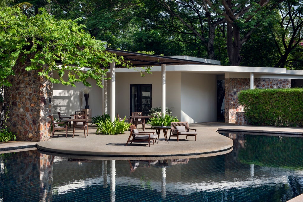 Serene courtyard pool at Amansara resort, surrounded by minimalist white architecture and tropical foliage under Cambodian sunlight