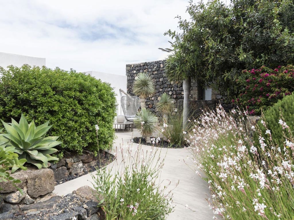 Luxurious Sicilian boutique hotel nestled against rustic stone walls, with elegant white-washed architecture and minimalist Mediterranean design elements