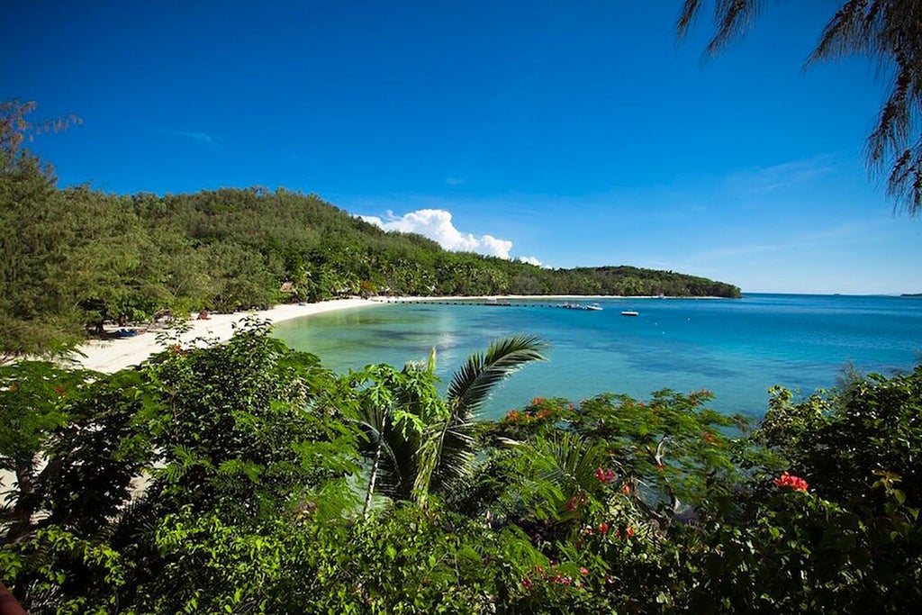 Luxurious Fijian beachfront villa with traditional thatched roof, wooden deck overlooking turquoise ocean, and lush tropical greenery surrounding Vonu Point Villa