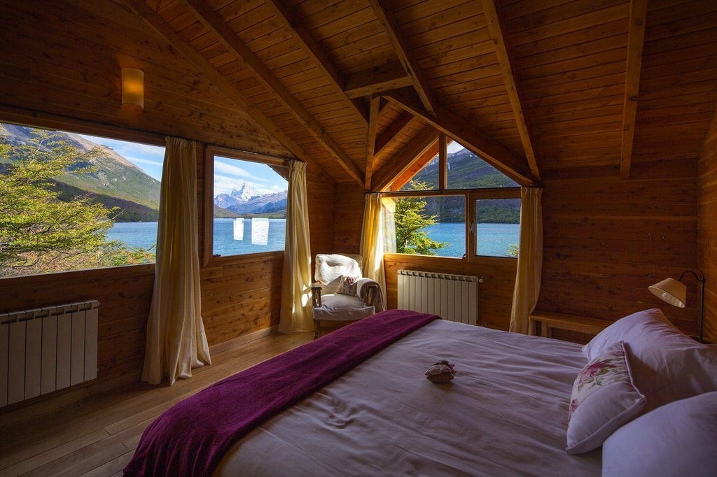 Rustic-luxe lakeside lodge with wood facade and stone accents nestled among lush Patagonian forest beside mirror-like alpine waters