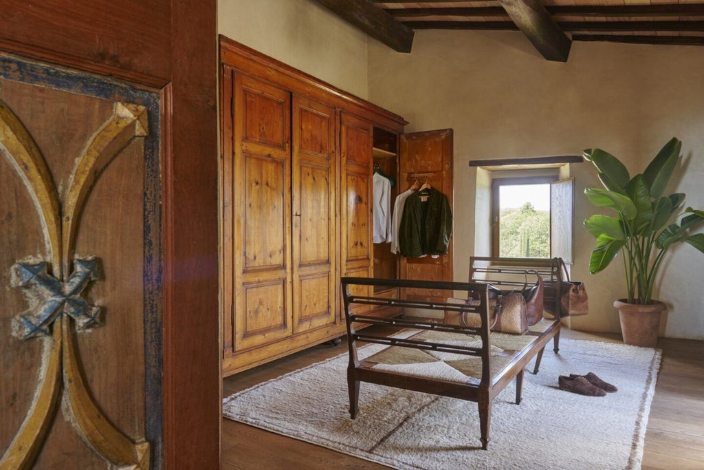 Elegant stone-walled suite in Tuscan villa, featuring rustic wooden beams, antique furnishings, and panoramic countryside views through large arched windows.