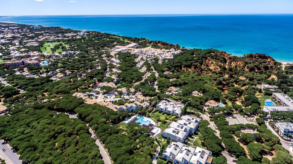 Luxurious seaside resort perched atop red cliffs, featuring Mediterranean architecture, manicured gardens, and ocean views