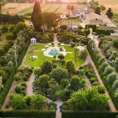 Luxurious Sicilian villa with stone walls, lush gardens, and elegant outdoor seating area surrounded by vibrant Mediterranean landscape near Syracuse