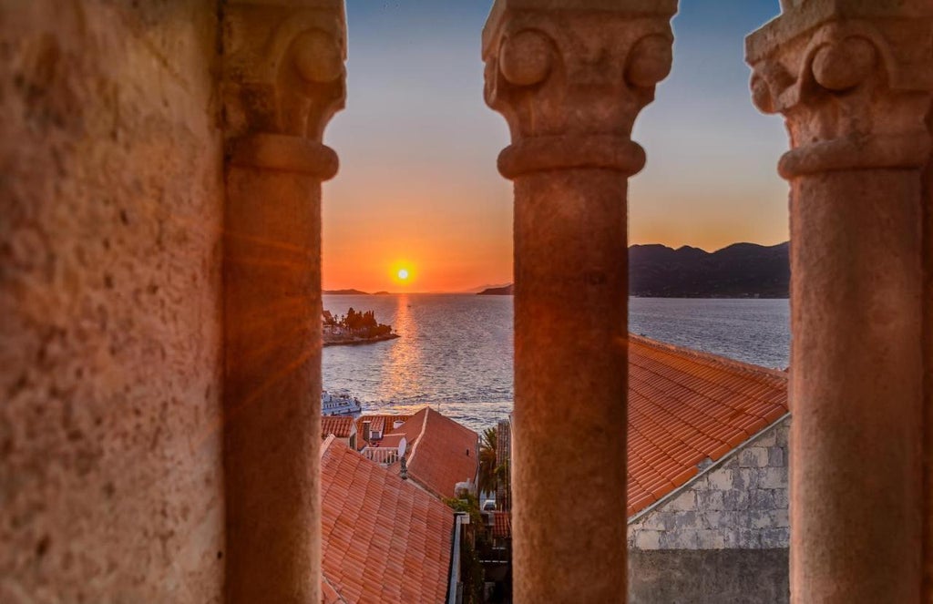 Elegant limestone facade of Lesic Dimitri Palace boutique hotel with wrought-iron balconies and arched windows overlooking Korcula bay