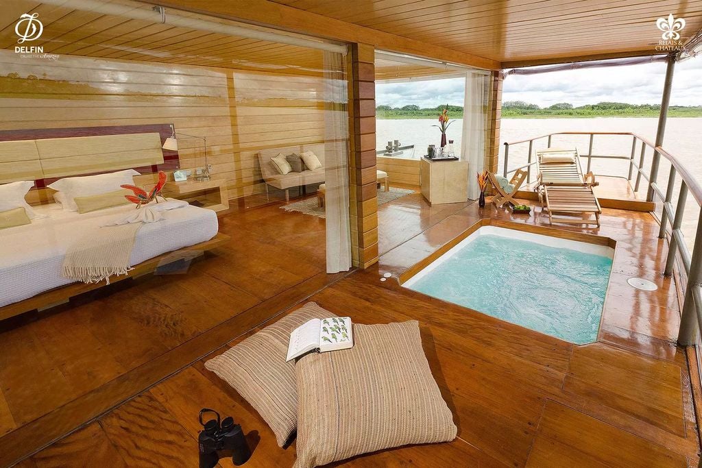 Luxurious wooden riverboat with floor-to-ceiling windows cruising through Amazon rainforest, featuring elegant open-air observation deck