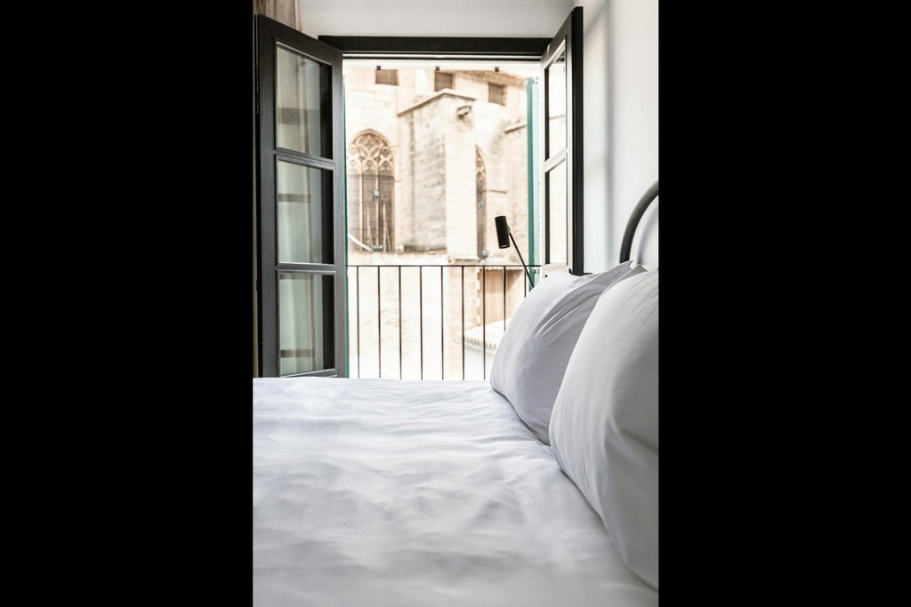 Elegant Mediterranean-style hotel room with plush white bedding, minimalist design, and private terrace overlooking scenic urban landscape in Spain