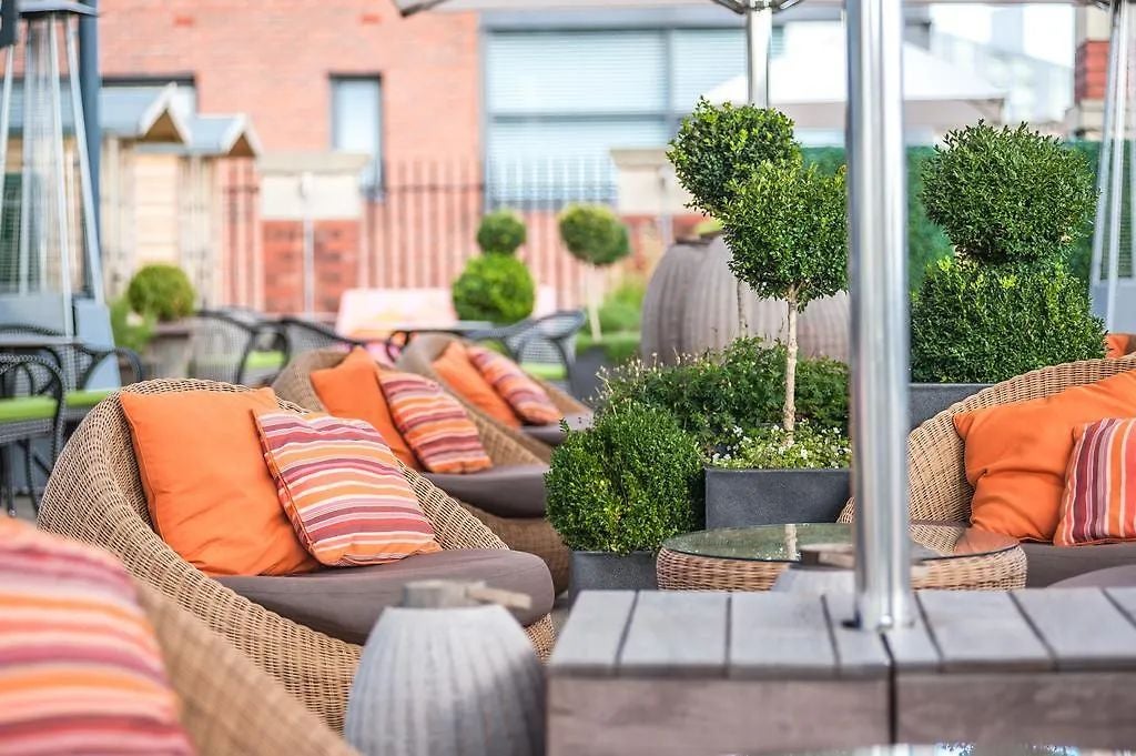 Boutique luxury hotel exterior with historic brick facade, elegant urban setting, distinctive architectural details in Manchester city center at dusk