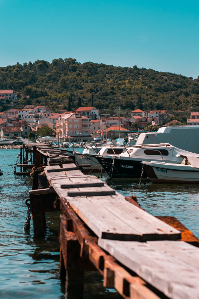 Local hosts serving premium Croatian wines on an elegant rooftop terrace with panoramic views of Trogir's historic skyline at sunset