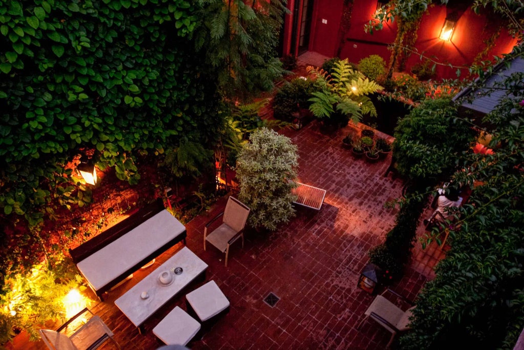 Luxurious hidden garden courtyard of boutique hotel with lush greenery, colonial-style architecture, and elegant outdoor seating area in Argentina