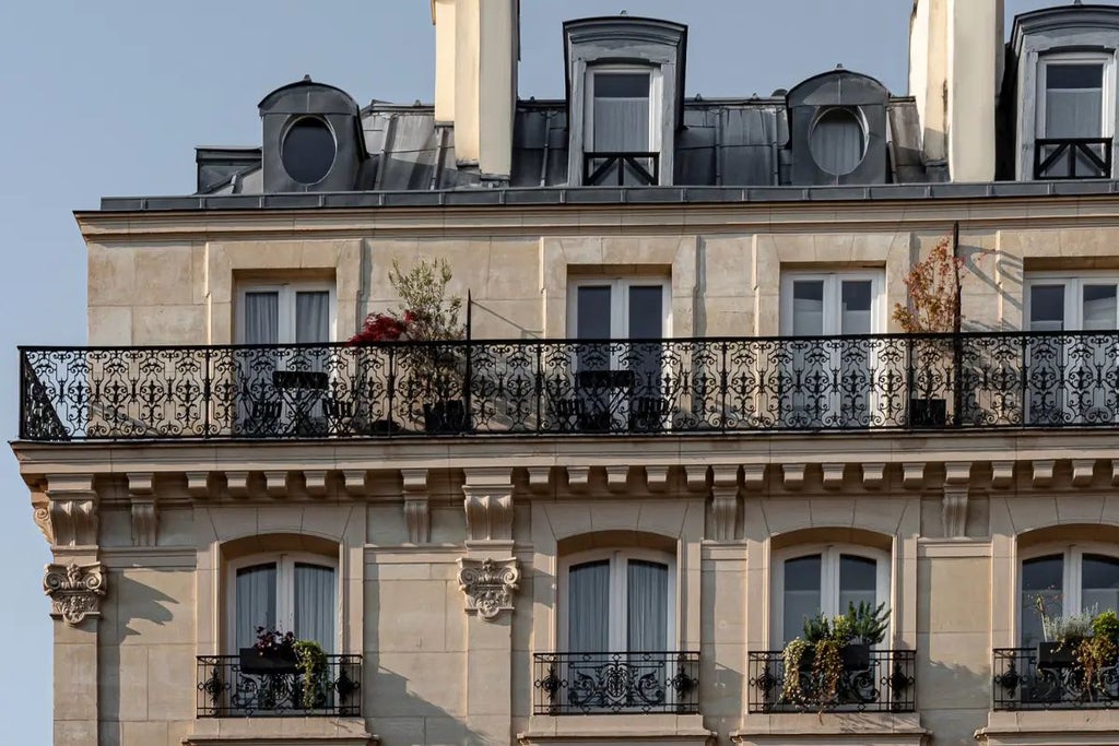 Elegant art deco boutique hotel with pink facade, ornate balconies, and vintage Parisian charm in the vibrant Grand Pigalle neighborhood of France.