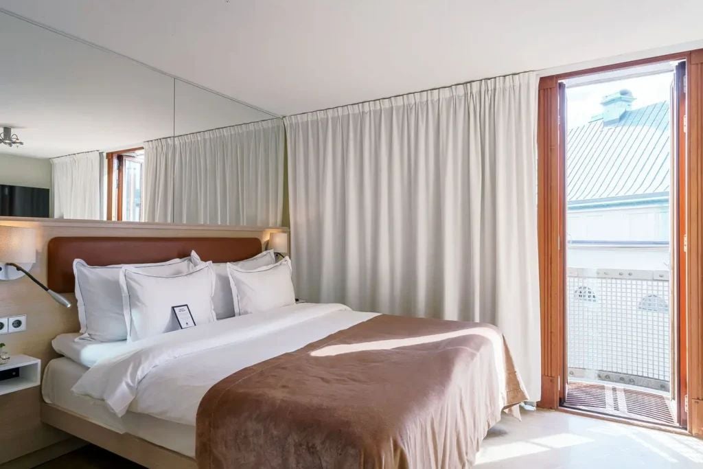 Elegant hotel room with dark wood furnishings, plush white bedding, minimalist design, soft lighting, showcasing Swedish luxury and contemporary style at Scenset Hotel.