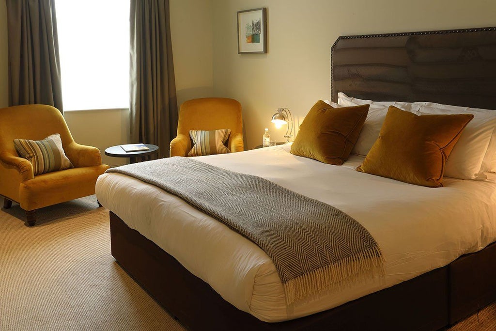 Luxurious superior hotel room with plush king-sized bed, elegant wooden furnishings, soft neutral tones, and large window overlooking scenic landscape in United Kingdom