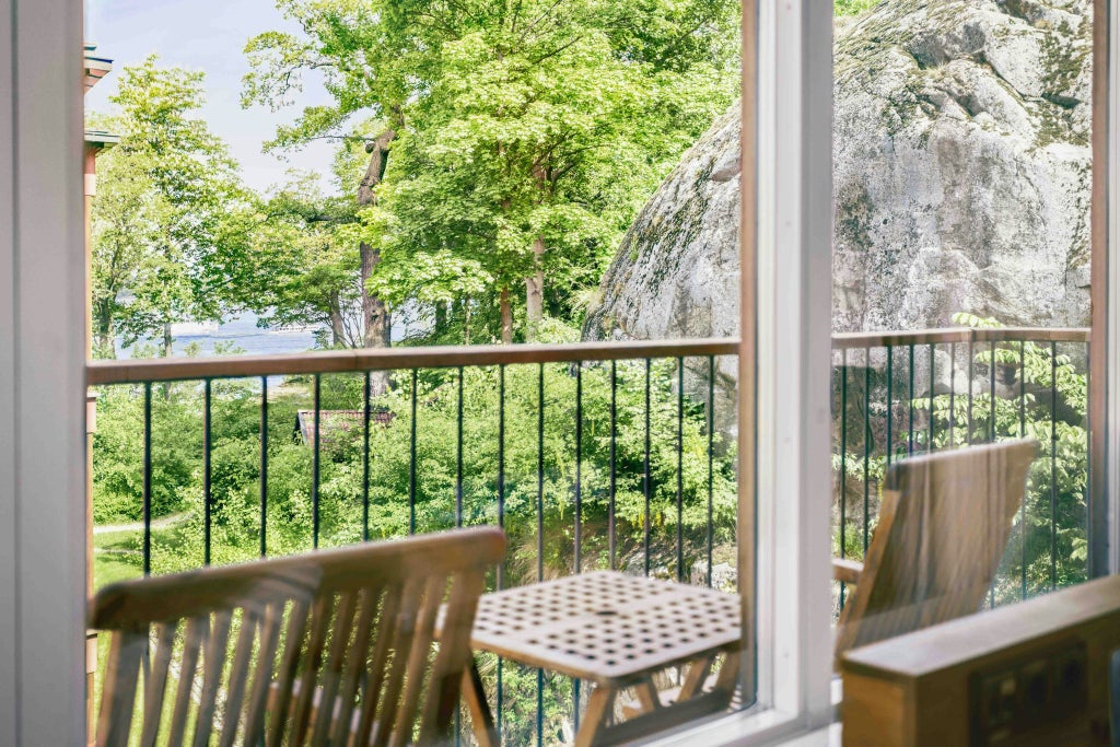 Spacious Scandinavian-style deluxe family room with modern wooden furnishings, crisp white linens, and panoramic city view in a contemporary Swedish hotel