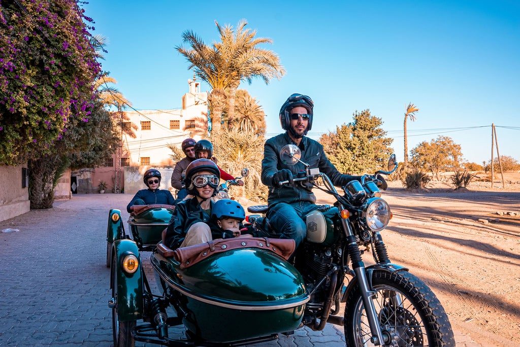 Motorcyclists cruise past ornate Moorish architecture and bustling souks in Marrakech, with luxury vintage bikes gleaming in desert sun