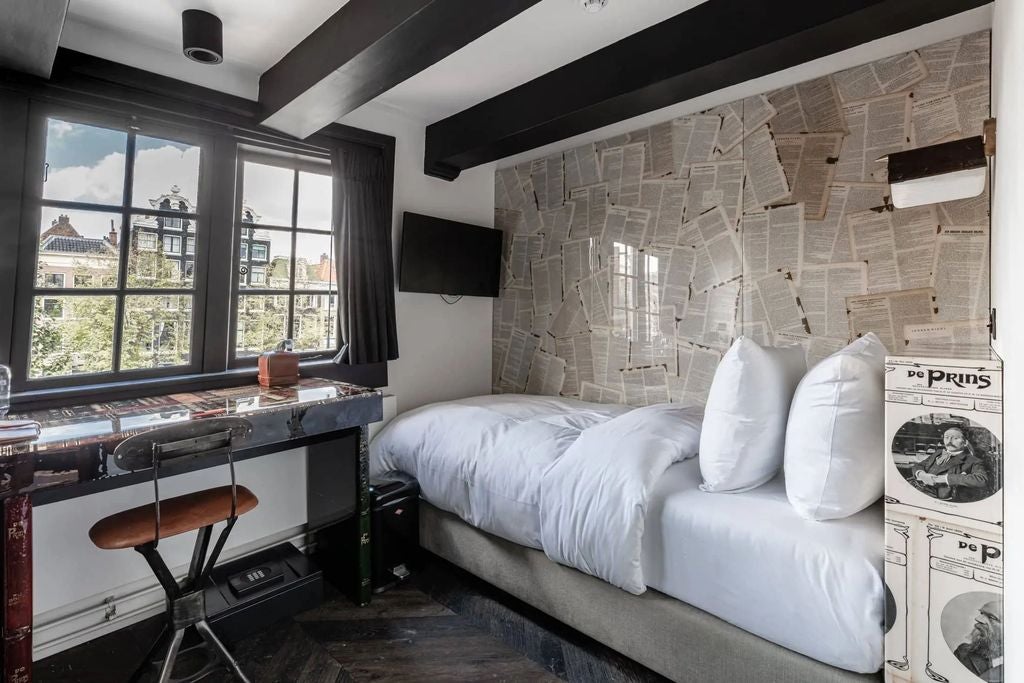 Historic Dutch boutique hotel with charming brick facade, featuring ornate white window frames and traditional gable roof in Amsterdam