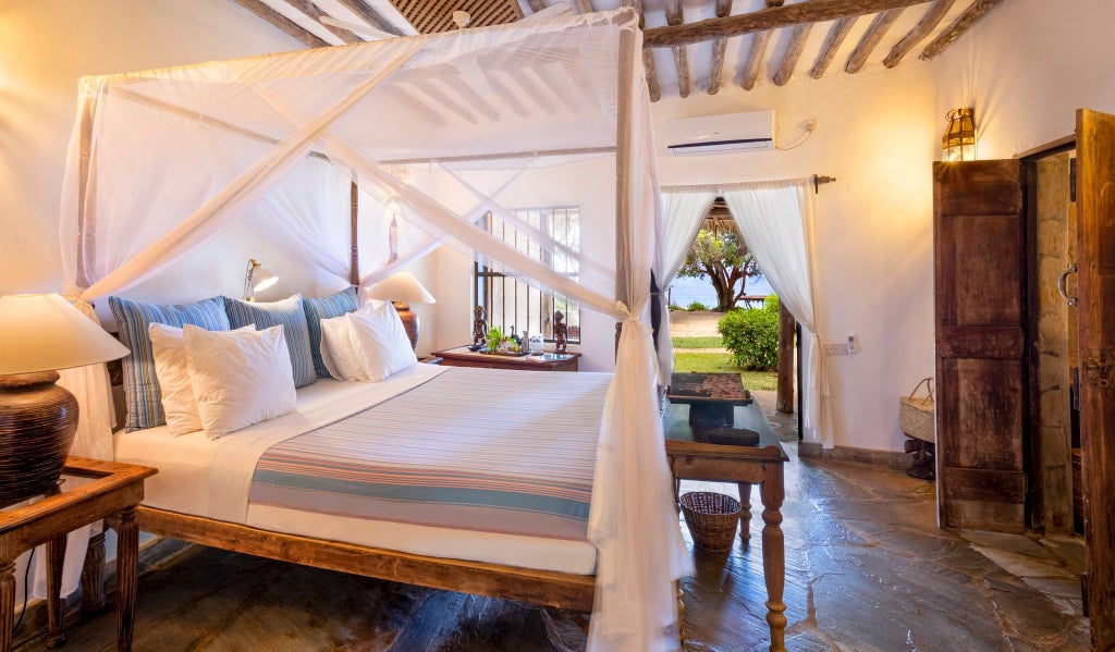 Luxurious coastal Kenyan villa with traditional thatched roof, white-washed walls, and elegant wooden furnishings overlooking lush tropical gardens near the ocean.