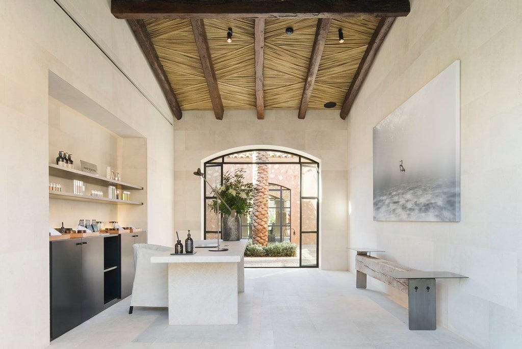 Historic Spanish villa with stone facade, arched windows and rustic wooden shutters surrounded by Mediterranean gardens and pool