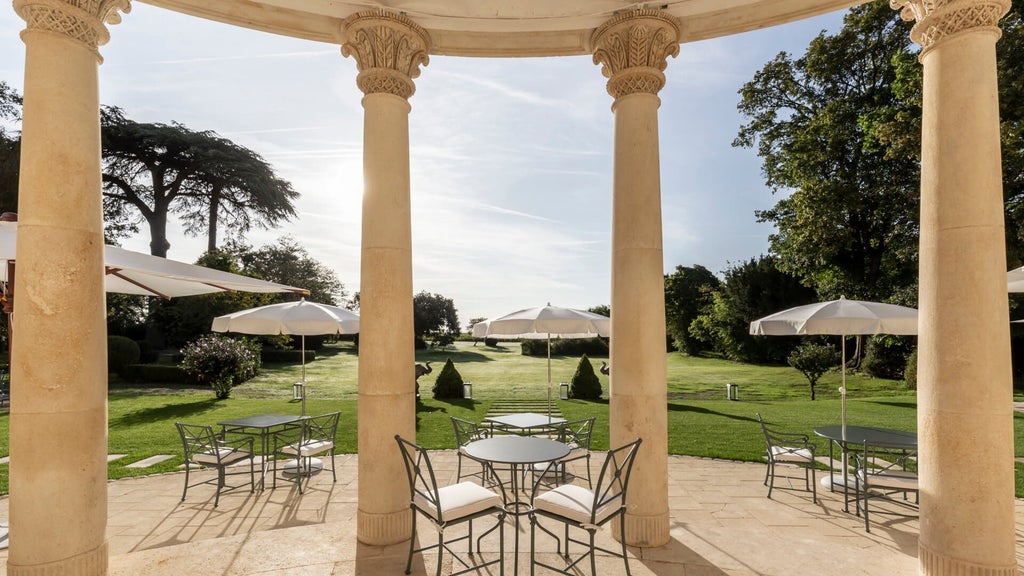 Elegant French château-style hotel with manicured gardens, stone facade, and lush vineyard backdrop, showcasing timeless luxury in scenic wine country