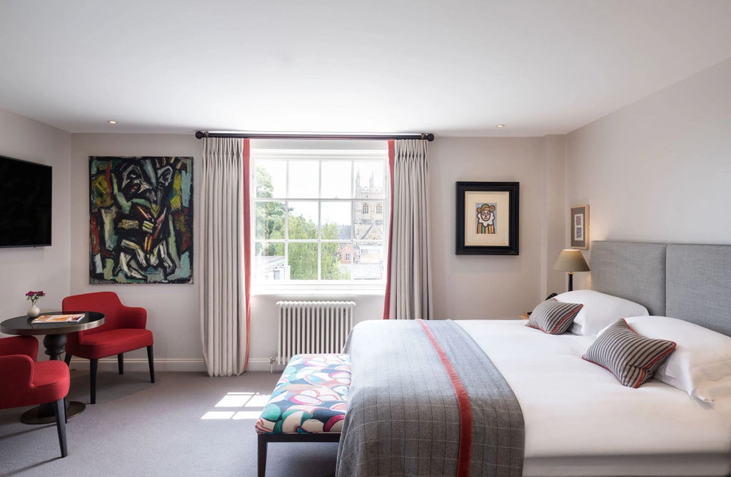 Elegant classic hotel room with rich wooden furnishings, crisp white linens, period architectural details, and soft ambient lighting in a historic United Kingdom setting