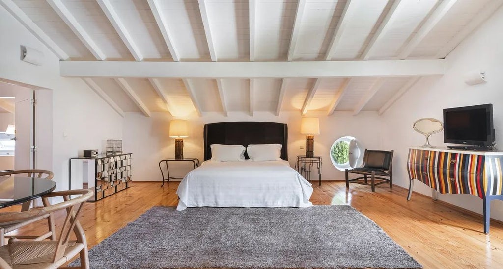 Elegant spacious suite with wooden floor, plush white bedding, minimalist design, large windows overlooking lush Portuguese countryside landscape