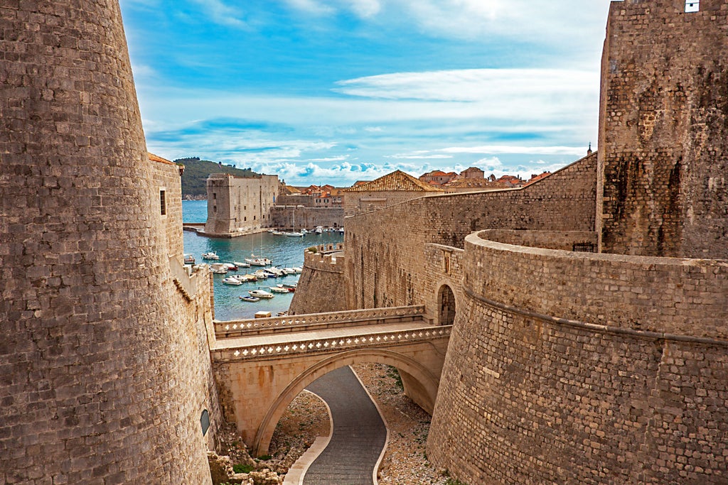 Group walks through narrow limestone streets of Dubrovnik's Old Town, passing historic orange-tiled roofs and medieval city walls