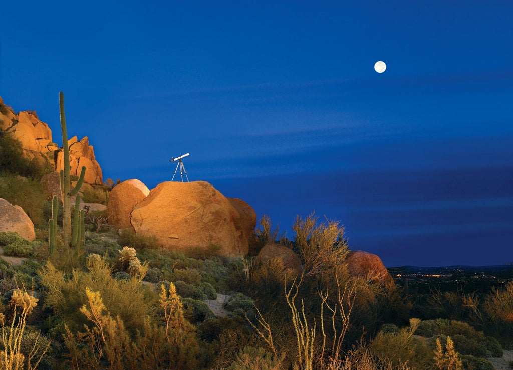 Luxurious desert resort featuring terra cotta buildings nestled against dramatic red rocks, with manicured cactus gardens and serene pools