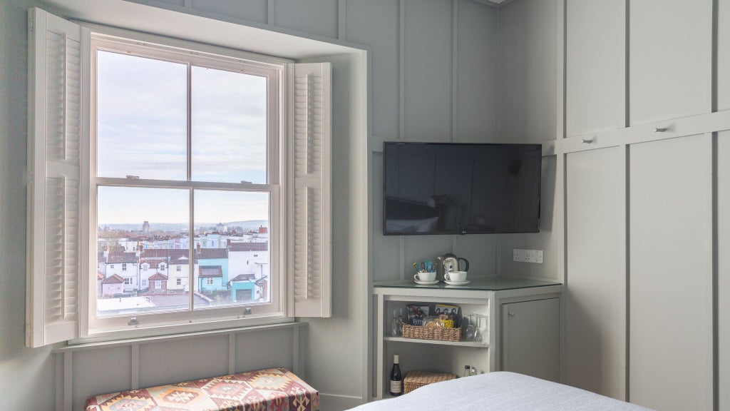 Elegant UK hotel room with modern bath and shower, featuring sophisticated decor and crisp white linens in a stylish, contemporary accommodation space